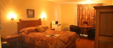 A hotel room with a large bed, a desk, a chair, and a small table.