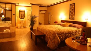 Een hotelkamer met een bed, nachtkastje en een badkamer met wastafel en spiegel.