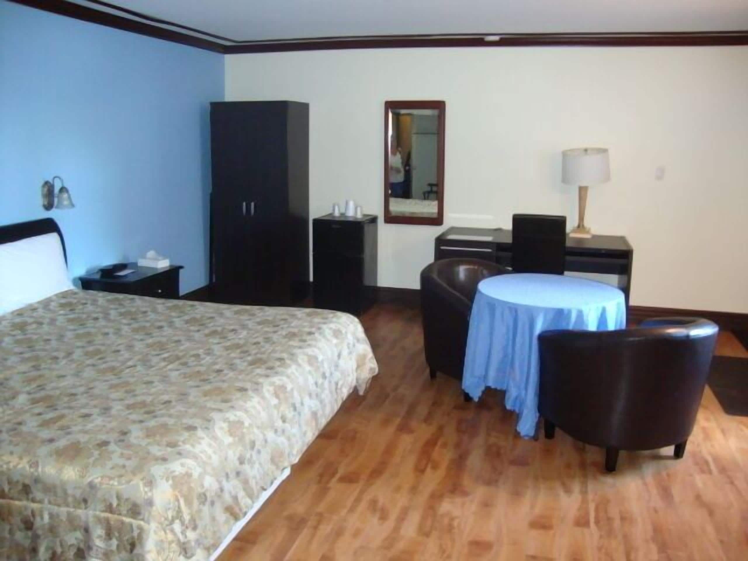 Une chambre d’hôtel comprenant un lit, un bureau, une chaise, une table et une armoire.