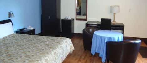 Une chambre d’hôtel comprenant un lit, un bureau, une chaise, une table et une armoire.