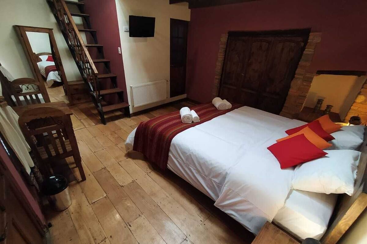 A bedroom with a wooden bed, a red and white striped blanket, and a wooden chair.