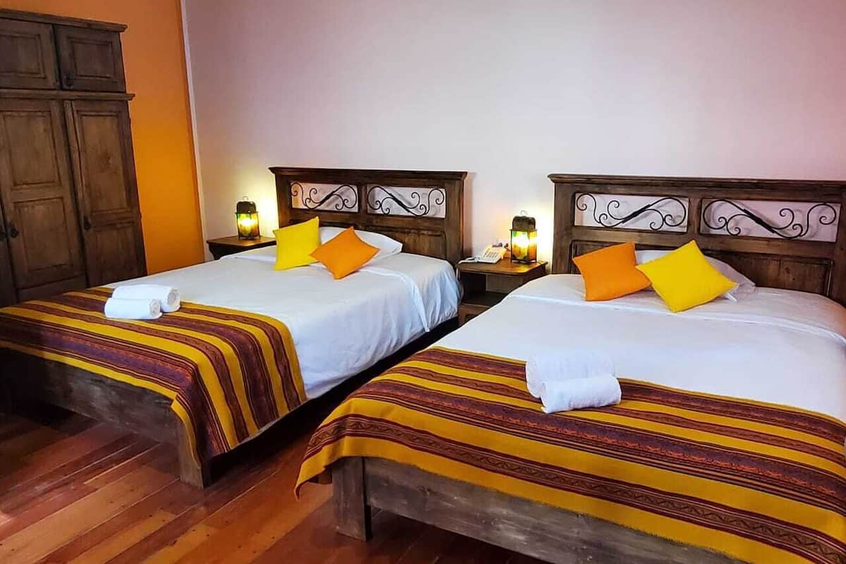 Two single beds with striped bedding, wooden headboards, bedside lamps, and a wooden wardrobe.