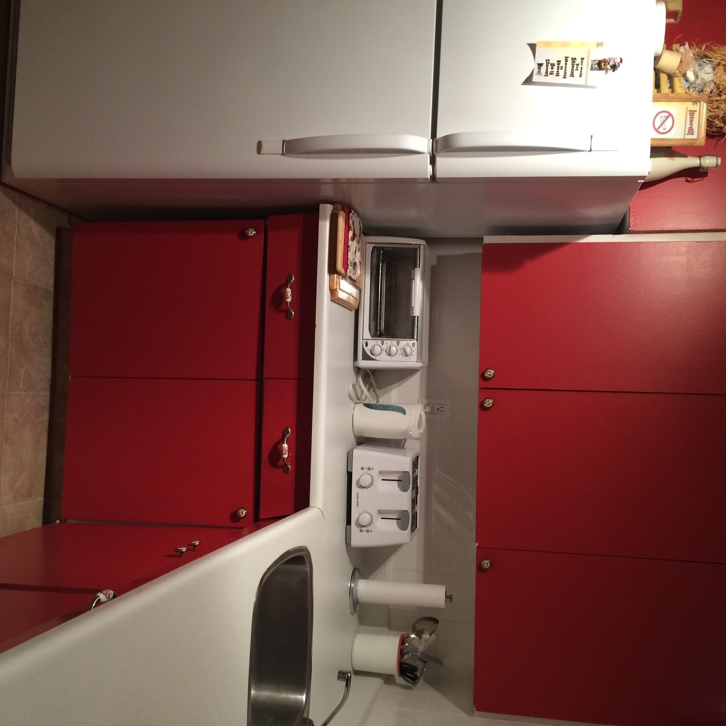 Un baño con un mueble rojo, un lavamanos blanco y un espejo.