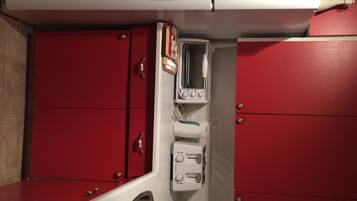 Un baño con un mueble rojo, un lavamanos blanco y un espejo.