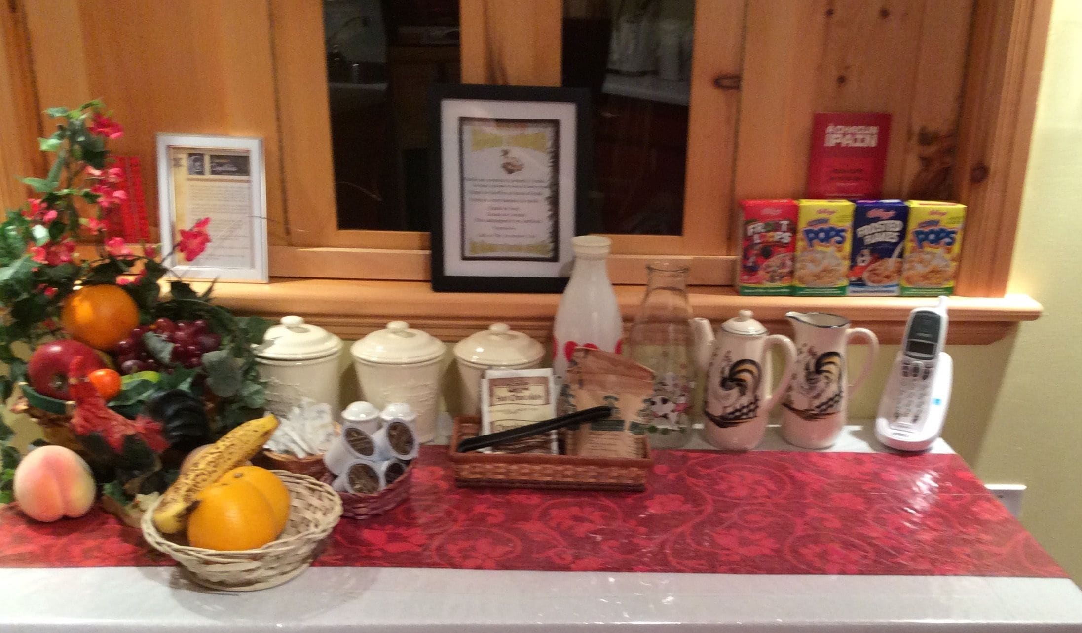 A kitchen counter with various items including a fruit bowl, jars, a bottle, and a phone.