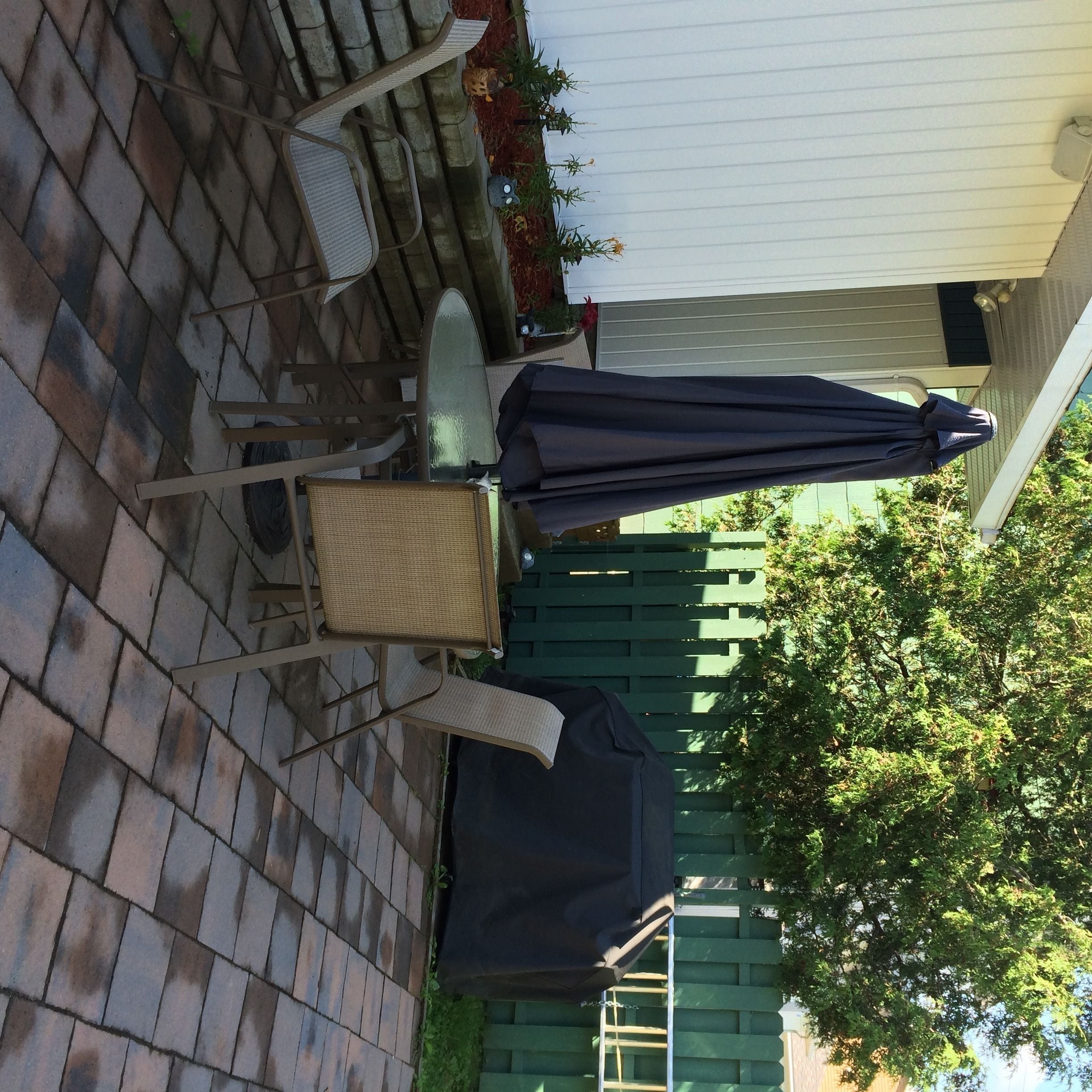 A patio with outdoor furniture, including a table and chairs, and a covered umbrella.