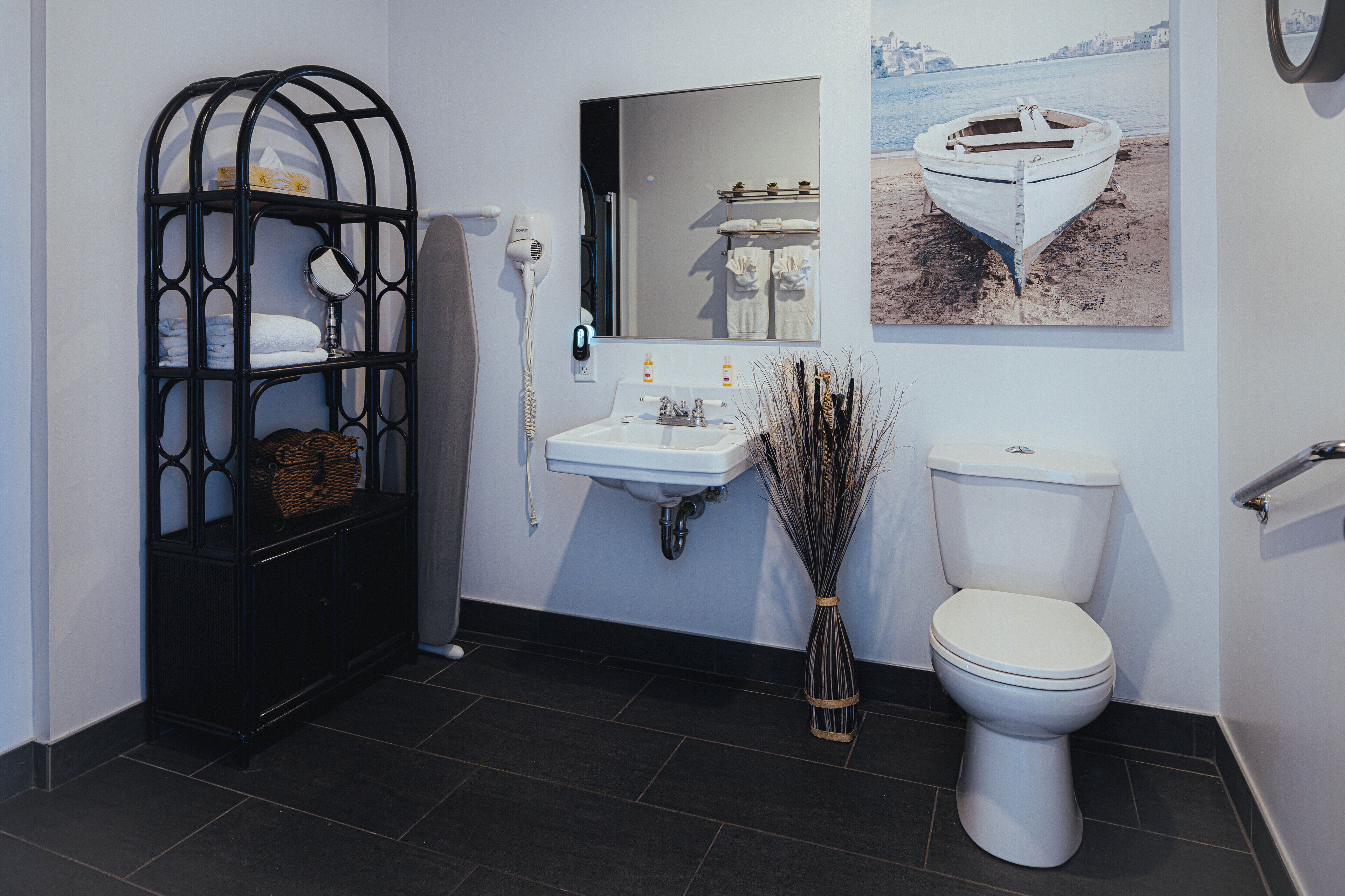 Un bagno con ripiano in metallo nero, lavandino bianco e water.