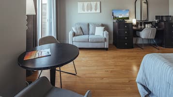 Habitación de hotel con sofá, escritorio, silla, cama y televisión.