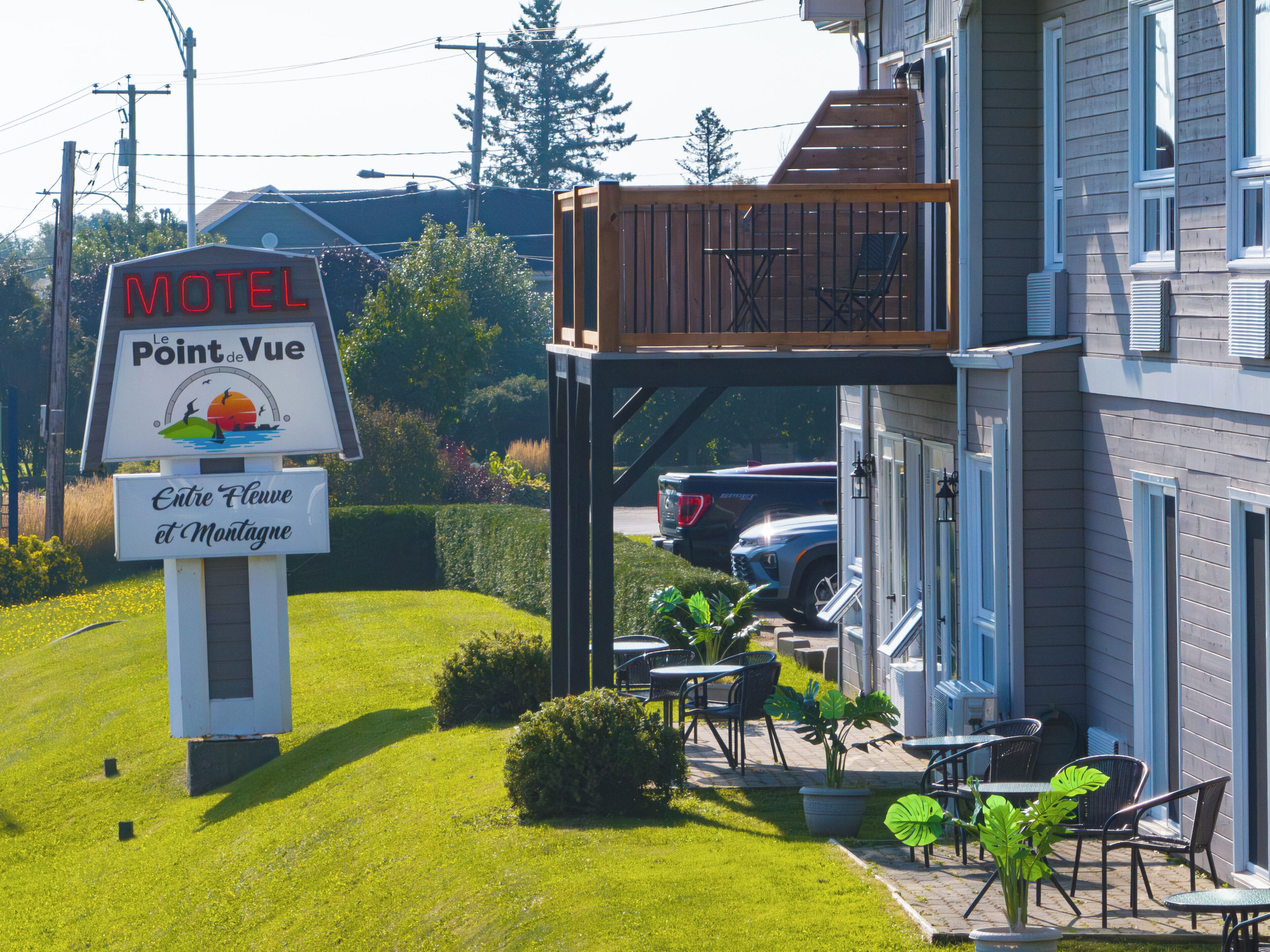 A motel with outdoor seating and a sign indicating it is located in Entre Fleuve et Montagne.