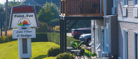 A motel with outdoor seating and a sign indicating it is located in Entre Fleuve et Montagne.
