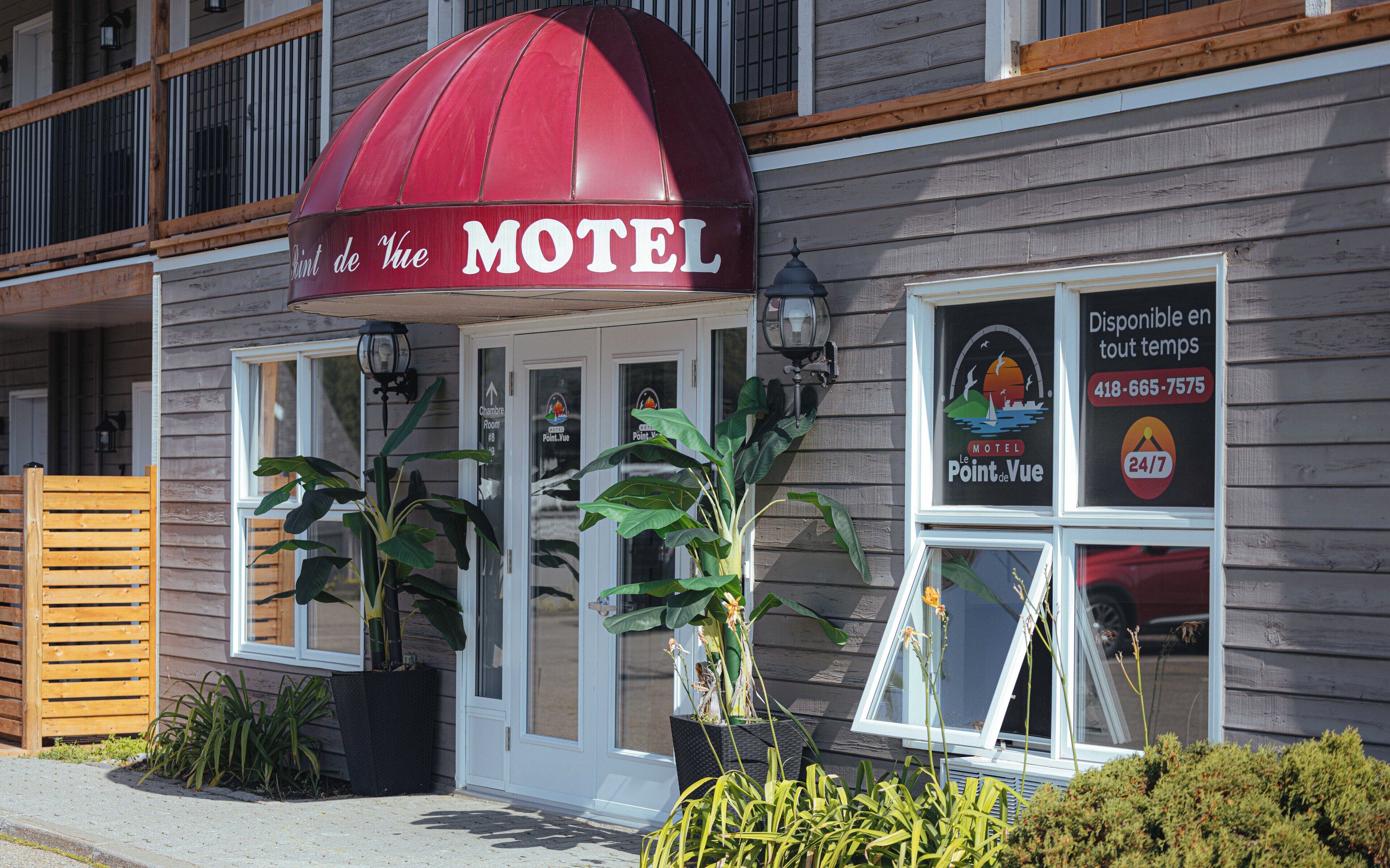 A motel with a red awning, a sign indicating availability, and a contact number.
