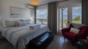 Een slaapkamer met een bed, een bankje, een rode stoel en uitzicht op de omgeving.