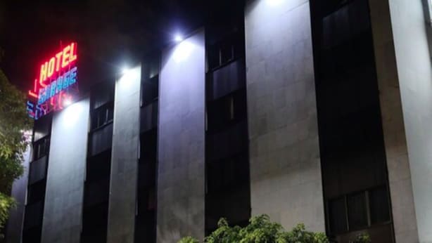 Un hotel con un llamativo letrero de neón, varios pisos y un estilo arquitectónico moderno.