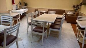 Un área de comedor con mesas y sillas, un extintor y un techo con tragaluces.