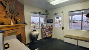 Zona de recepción con chimenea, planta, tablón de anuncios y un banco.