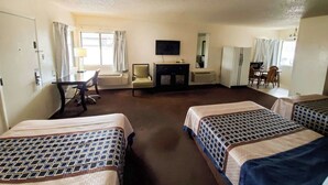 Habitación de hotel con dos camas, un escritorio, una silla, un televisor, un espejo y una ventana.