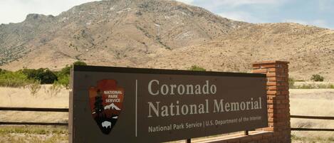 Skilt for Coronado National Memorial med et bjergrigt baggrundsmotiv.