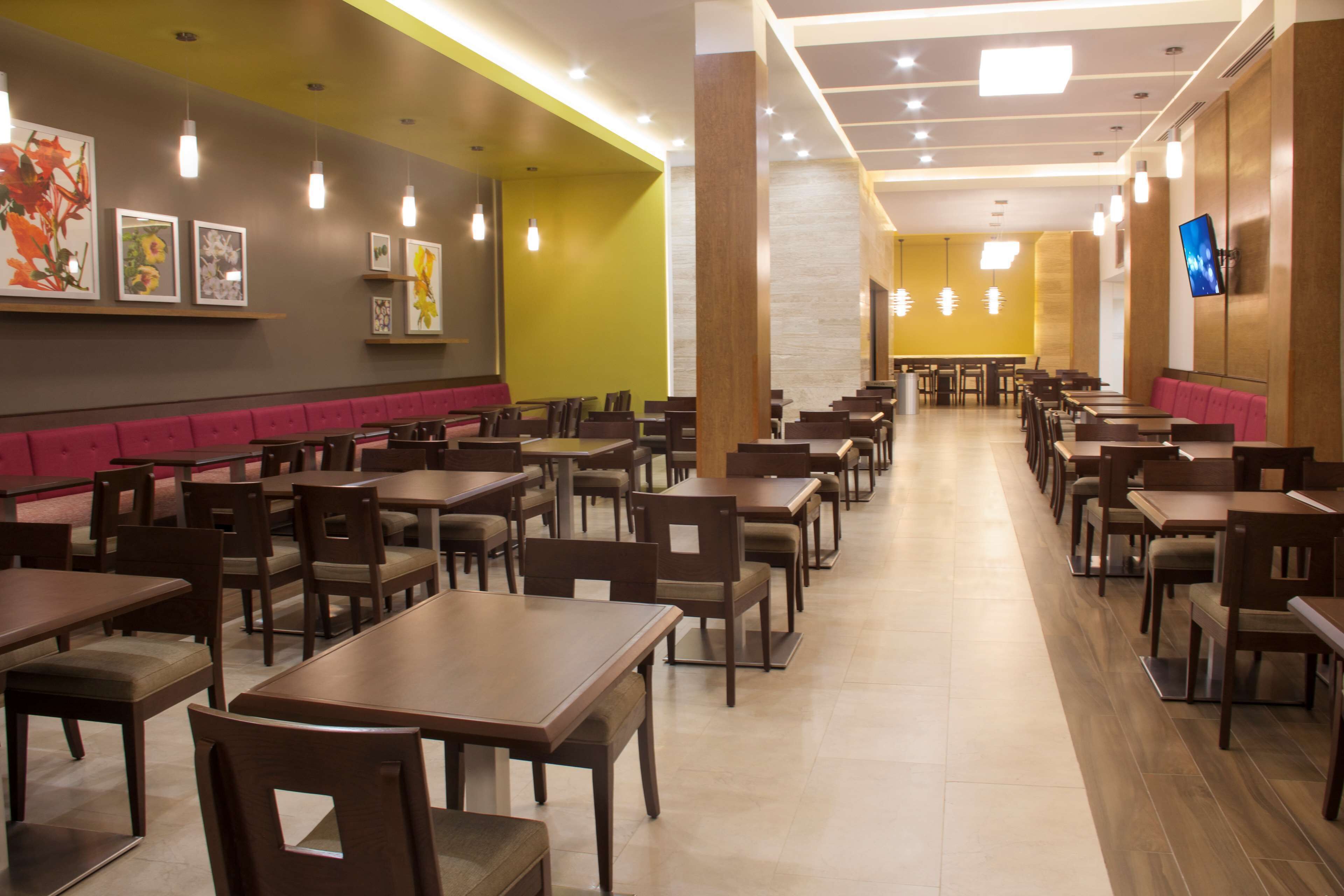 Un restaurante con varias mesas y cabinas, piso de madera y obras de arte en las paredes.