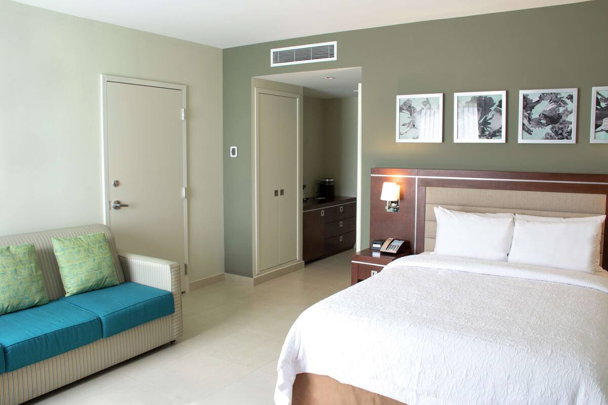 Une chambre d’hôtel avec un lit, un canapé, une commode et un miroir.
