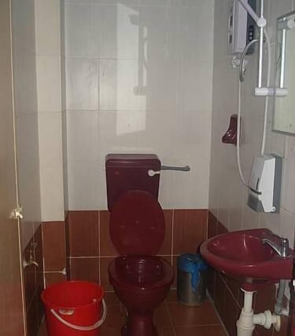 A bathroom with a toilet, a red sink, and a red bucket. - Kameleon Travellers Lodge (Kuala Lumpur)