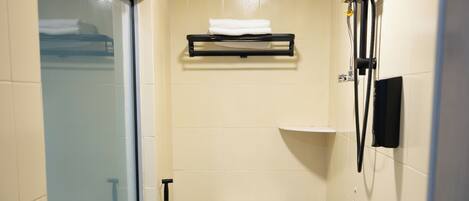 A compact bathroom with a toilet, a sink, a shower, and a window.