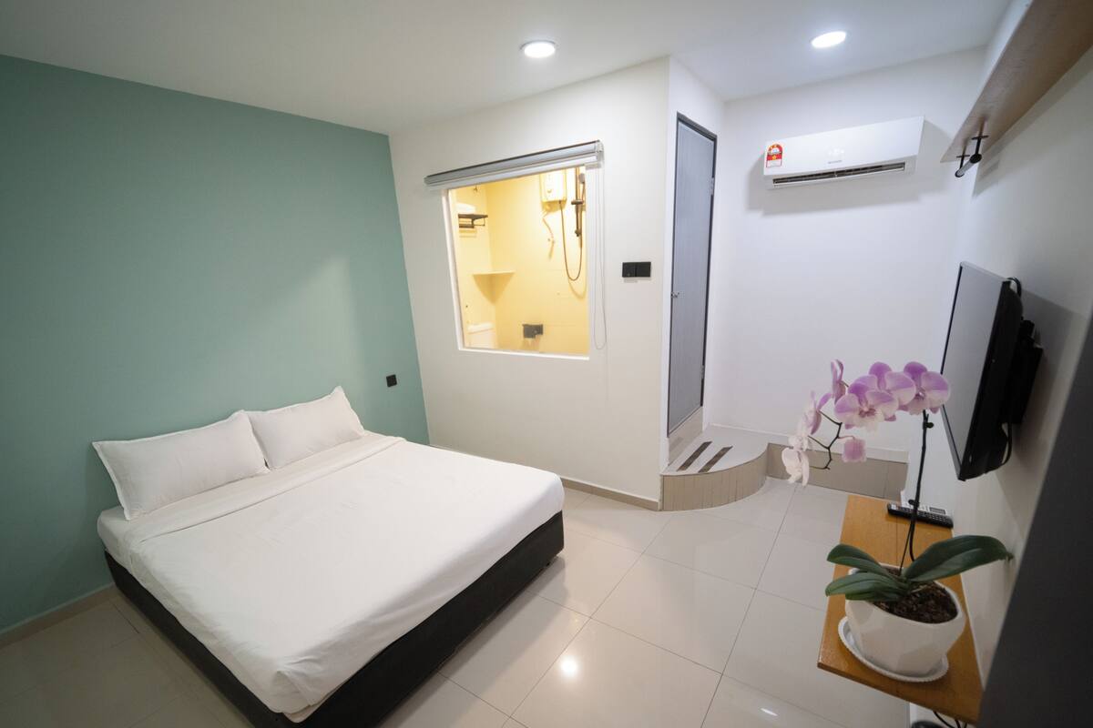 Une chambre moderne avec un grand lit, une fenêtre, une douche et un téléviseur.