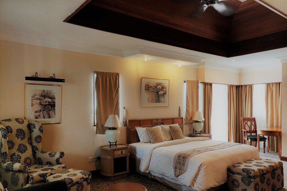 Una habitación de hotel con una cama, una silla, una mesa y un taburete pequeño.