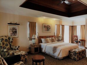 Una habitación de hotel con una cama, una silla, una mesa y un taburete pequeño.