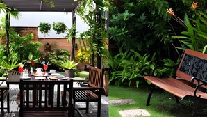 A patio with a table set for dining, surrounded by lush greenery and a wooden pergola. - VC. Pattaya (Pattaya)