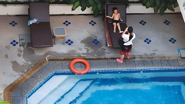 A swimming pool with a lifebuoy, a child lying on a lounge chair, and another child standing nearby. - VC. Pattaya (Pattaya)