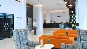 A modern lobby with a reception desk, seating area, and a glass elevator. - VC. Pattaya (Pattaya)