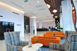 A modern lobby with a reception desk, seating area with sofas, and a staircase. - VC. Pattaya (Pattaya)