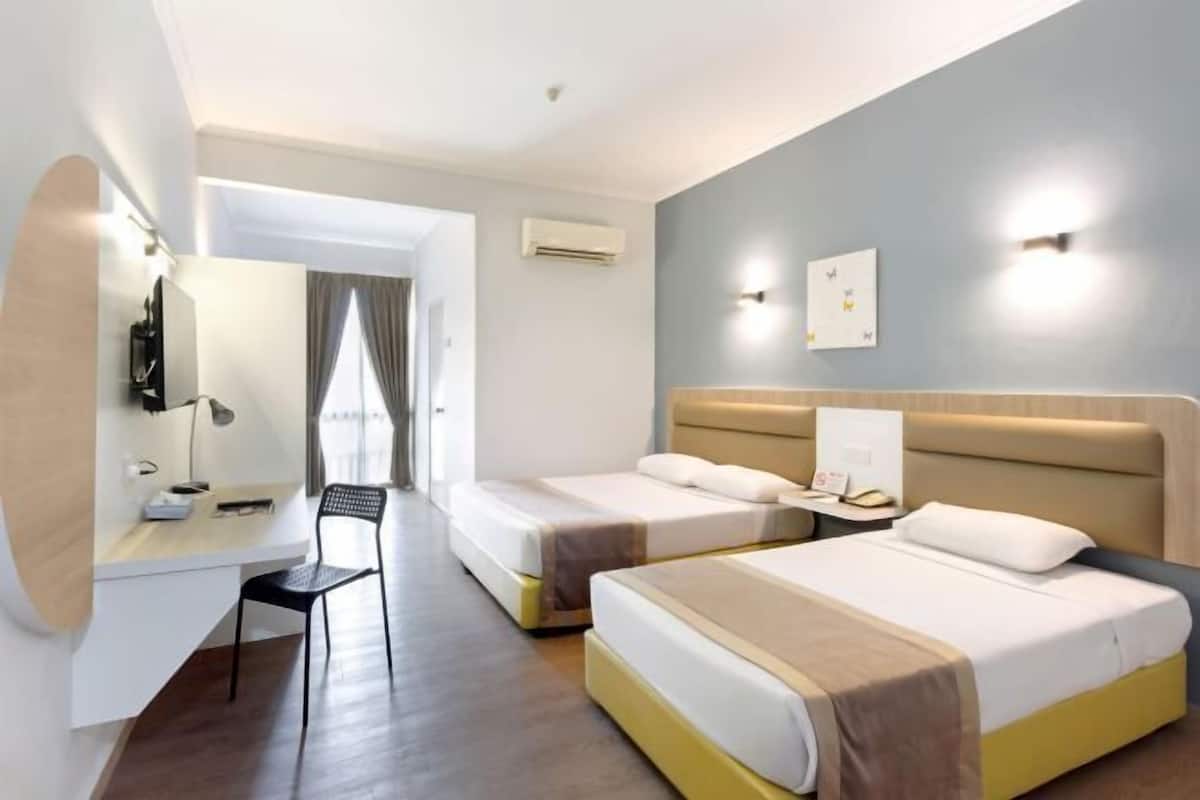 Une chambre d’hôtel avec deux lits, un bureau, une chaise et un miroir.