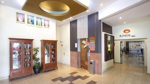 Una hall con una reception, un negozio Kings e tradizionali armadi di legno con piante in vaso.