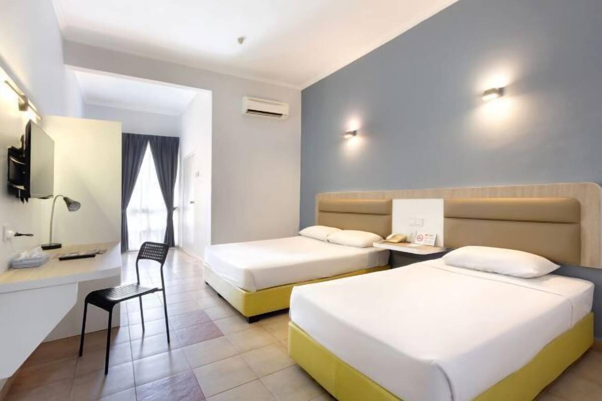 Une chambre d’hôtel avec deux lits, un bureau, une chaise et un téléviseur.