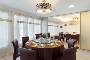 A dining area with round tables, chairs, and a chandelier. - Kings Hotel Melaka (Malacca City)