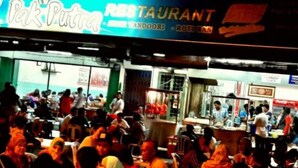 Un ristorante affollato con un cartello che riporta le scritte "Pak Putra" e "RISTORANTE".