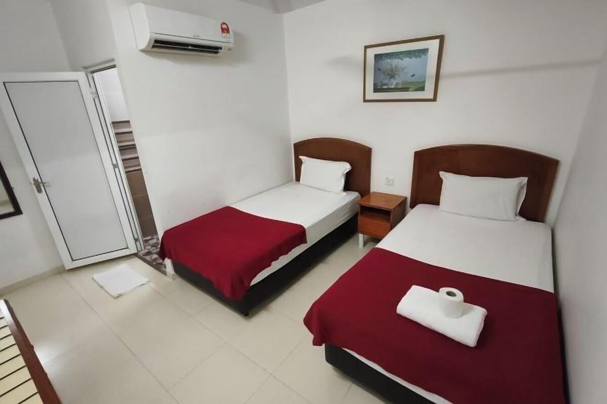 Habitación de hotel con dos camas, una puerta, un equipo de aire acondicionado y un cuadro en la pared.