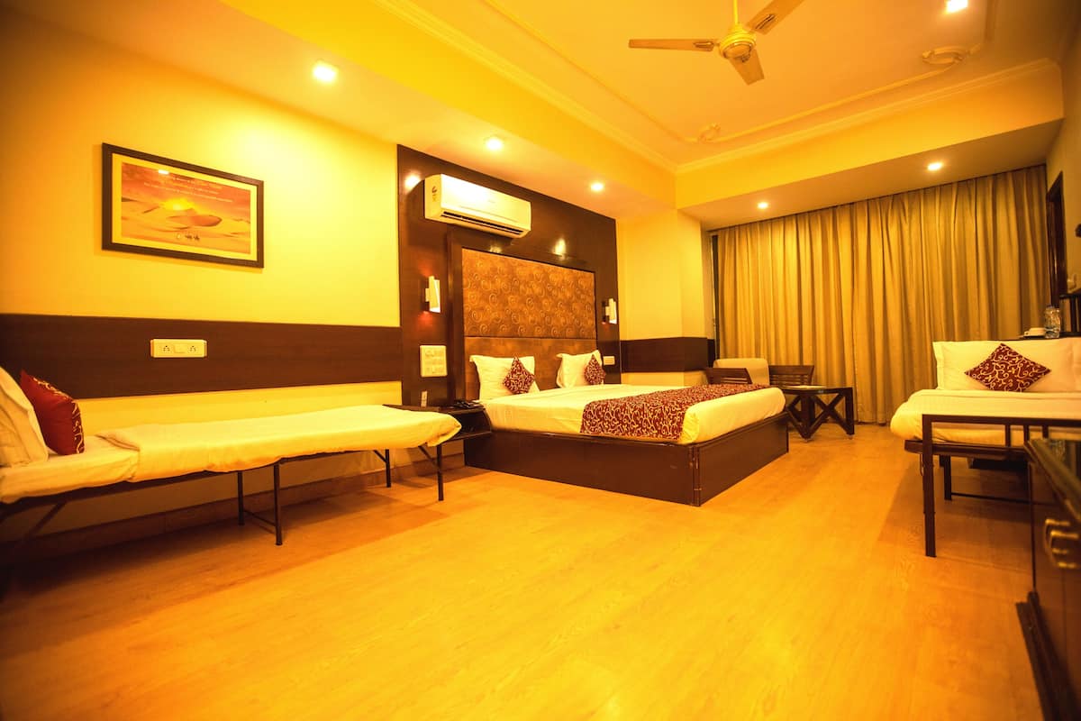 A hotel room with two beds, a desk, a chair, a ceiling fan, and an air conditioning unit.