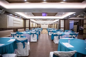 A conference room with rows of tables and chairs, each with a teal tablecloth and white chair covers tied with teal sashes. - Milestone 251 (Jaipur)