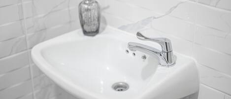 Un lavamanos blanco con grifo cromado y dispensador de jabón.