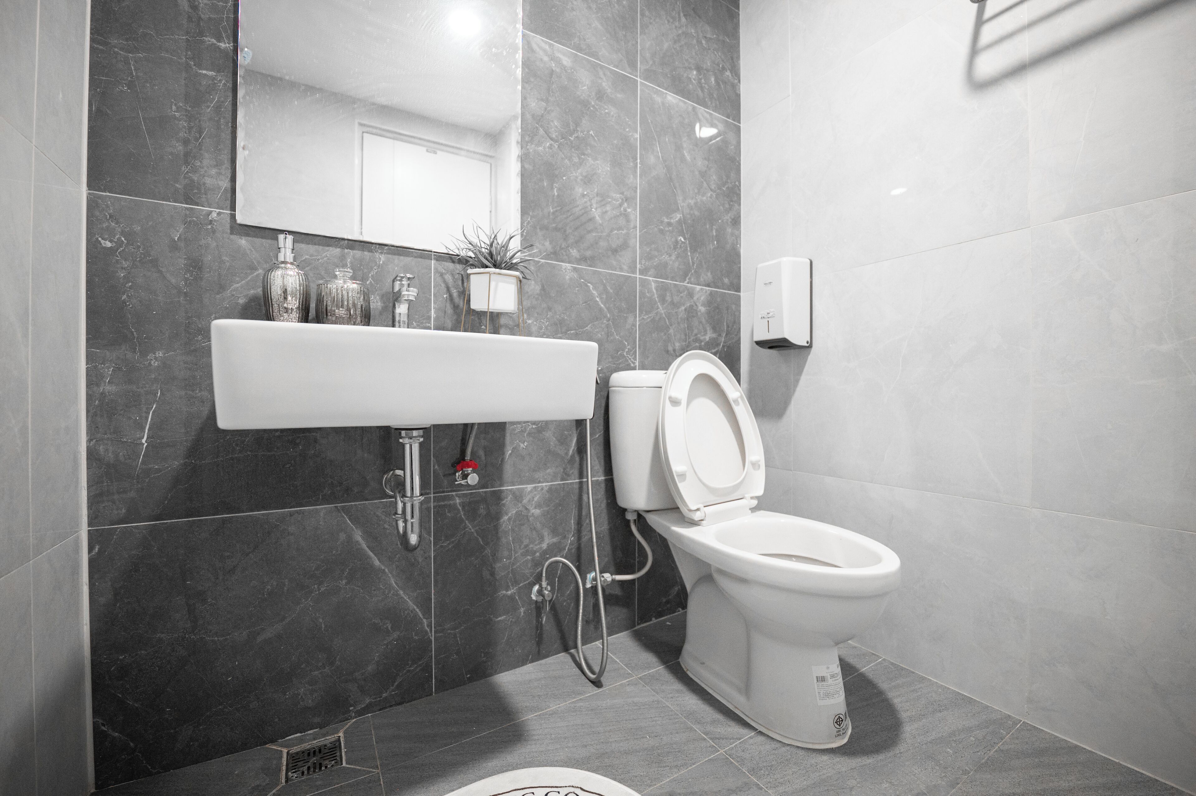 A modern bathroom with a white sink, a toilet, and a mirror.