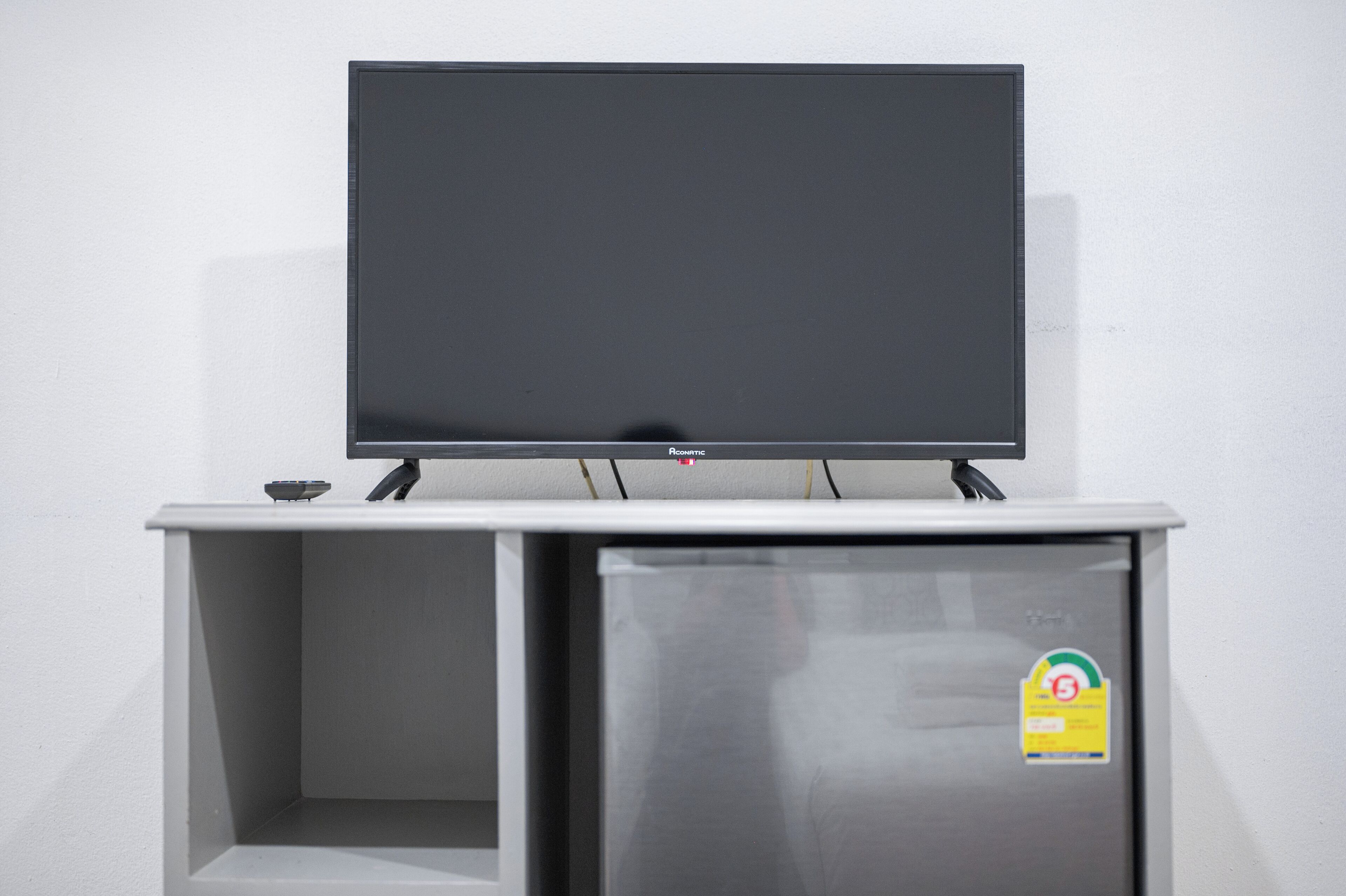A flat-screen TV mounted on a white cabinet with a small object on top.