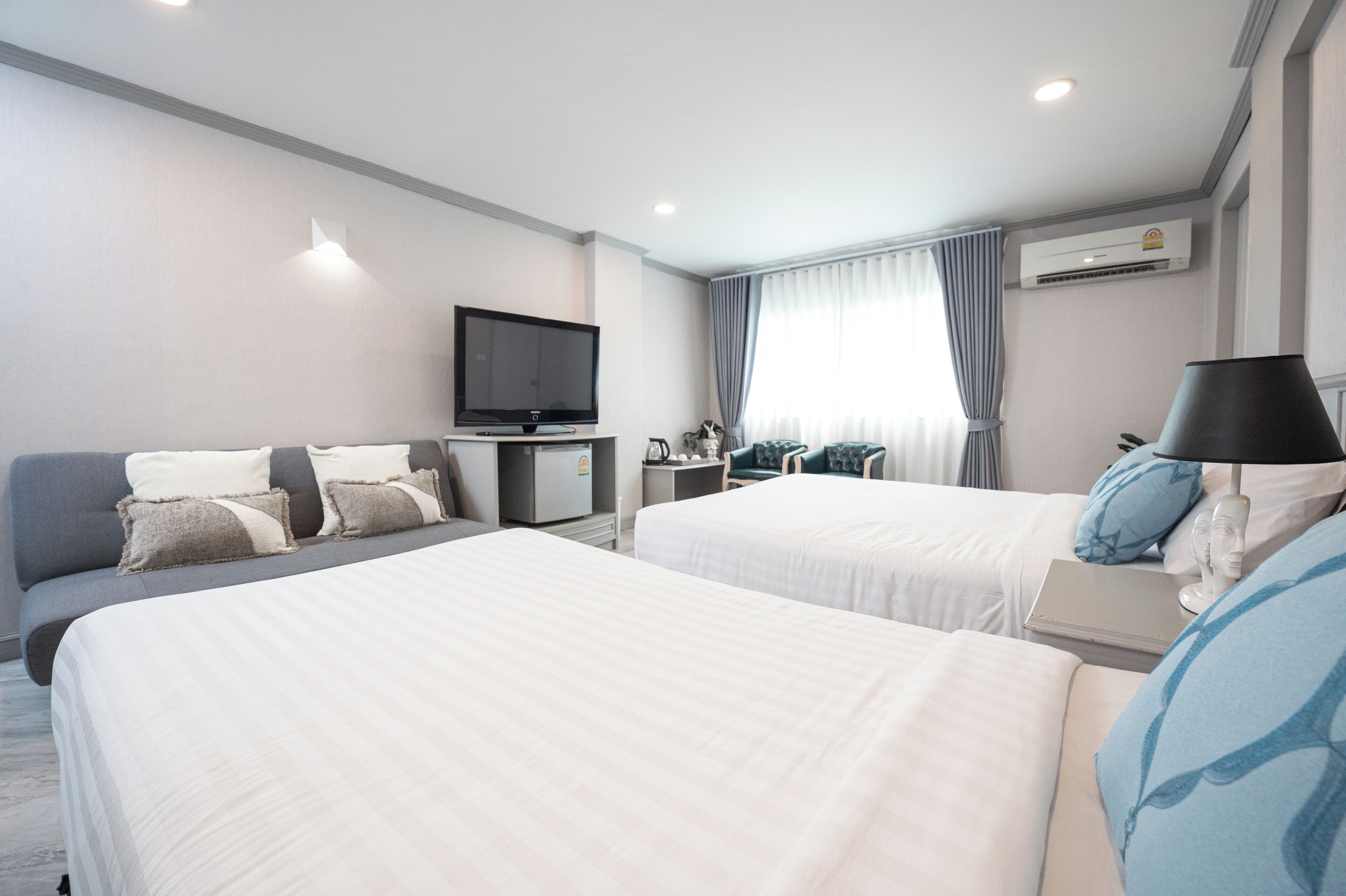 A hotel room with two beds, a TV, a desk, and a chair.