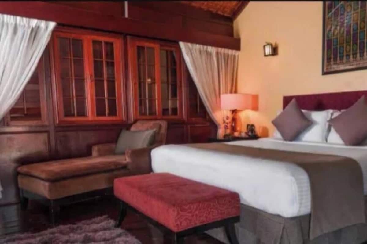 A room with a bed, a chair, a small table, and a lamp.