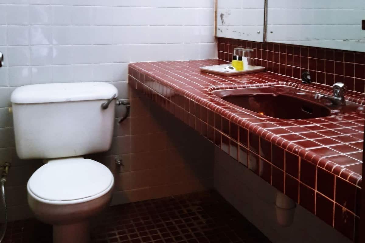 A bathroom with a toilet, a sink with a mirror, and a shelf with towels.