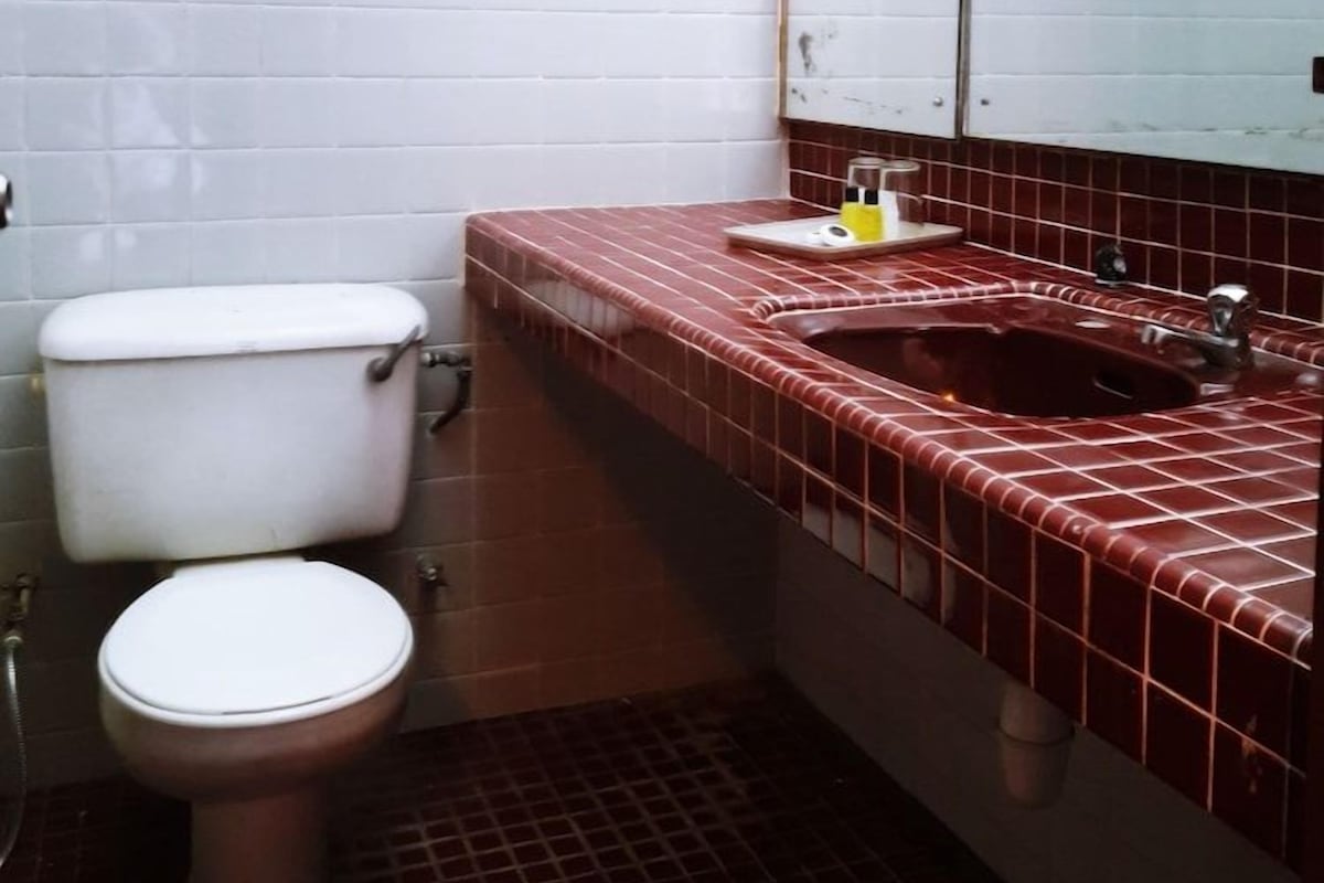 A bathroom with two toilets, a sink with a mirror, and a towel rack.
