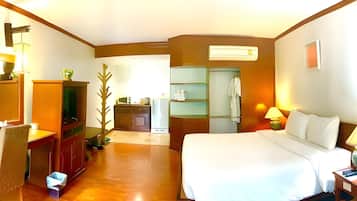 A hotel room with a bed, a desk, a chair, a TV, a wardrobe, and a bathroom visible through an open door.