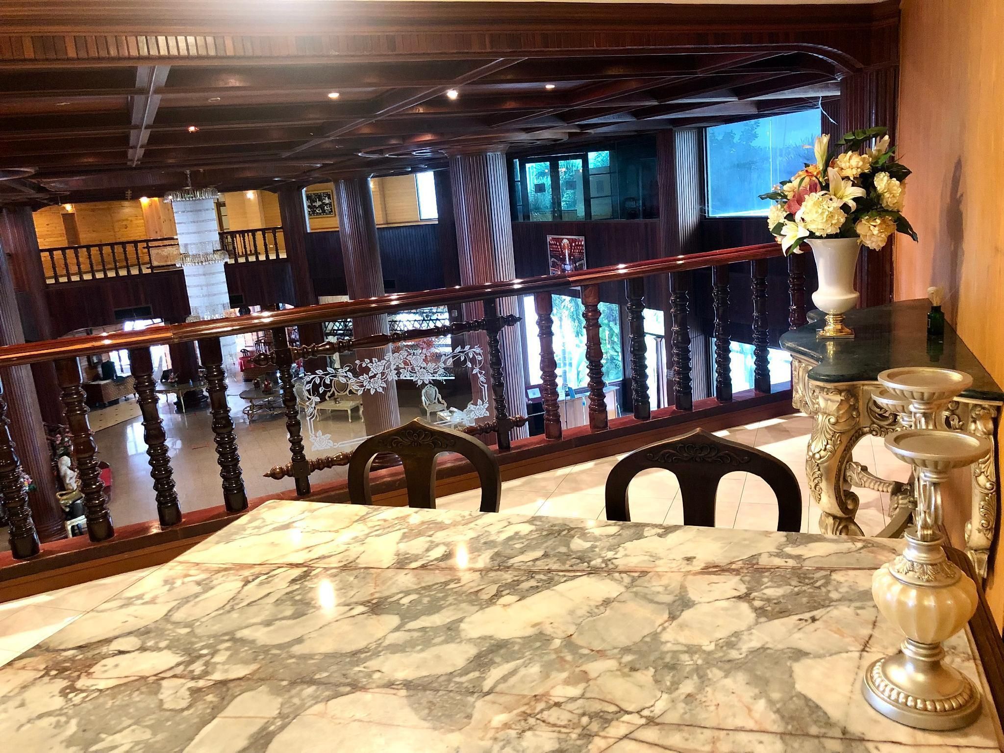 Une table surmontée d’un plateau en marbre, offrant une vue sur un balcon doté de balustrades en bois et agrémenté d’un vase de fleurs.