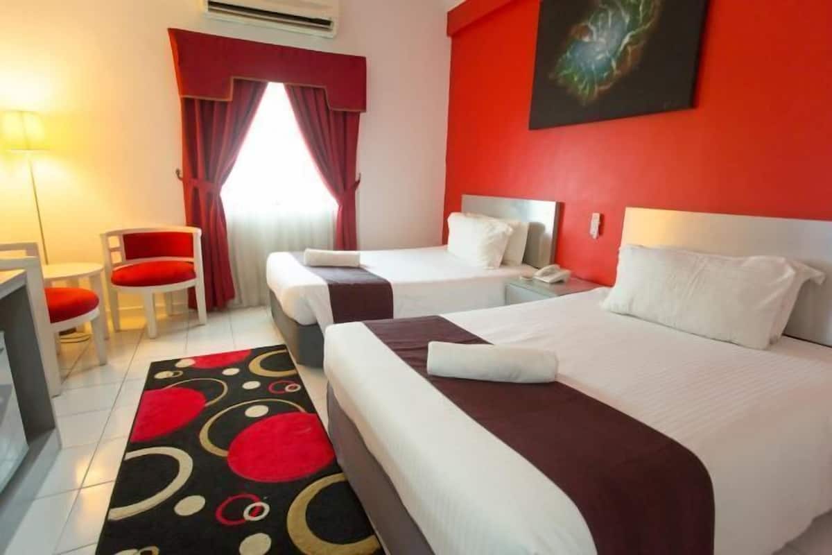 Hotellihuone, jossa on kaksi sänkyä, työpöytä, tuoli ja punainen seinä.